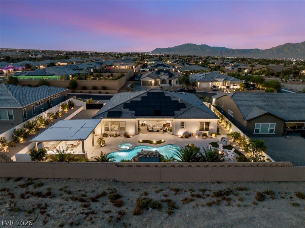 Dusk skies frame a spectacular desert backyard oasis complete with a pool, spa, and mountain views.