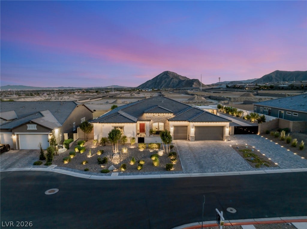Dramatic mountain backdrops frame this modern single-story residence with a paved driveway.