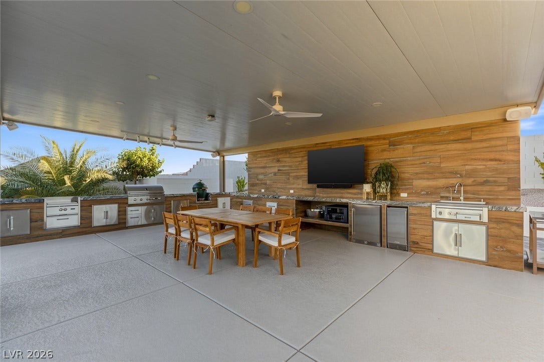 An expansive covered patio features a fully equipped outdoor kitchen and a spacious dining area.