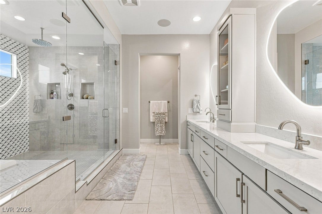 Double vanities and an expansive glass-enclosed shower highlight this modern primary bath.