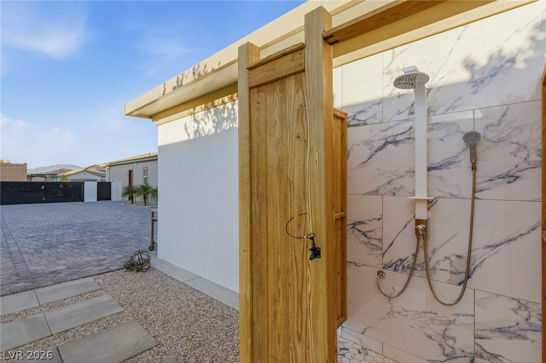 Marble-patterned tile and natural wood accents elevate this convenient outdoor shower setup.