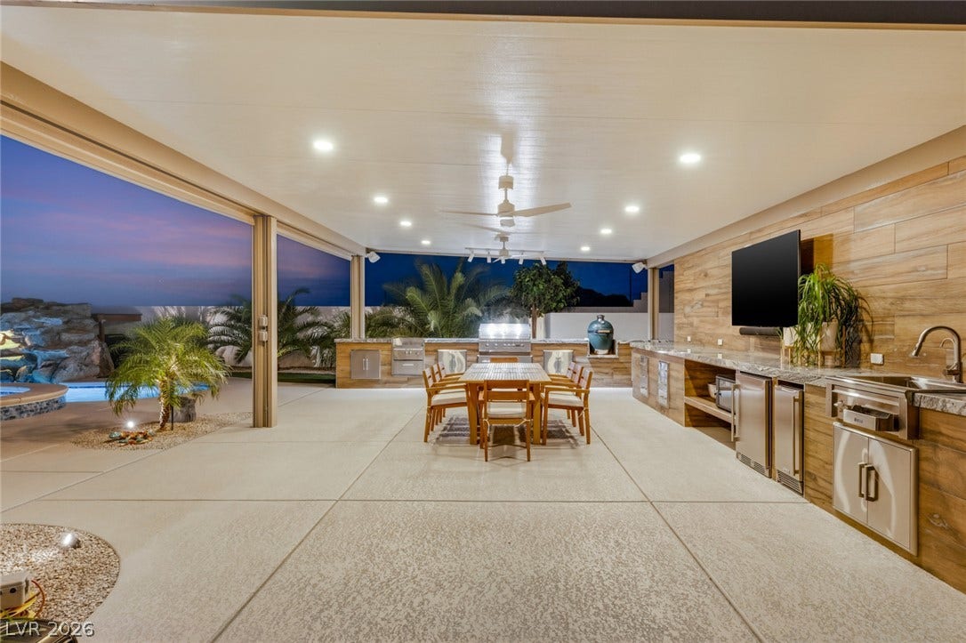 An expansive covered patio features a fully equipped outdoor kitchen beside the pool.