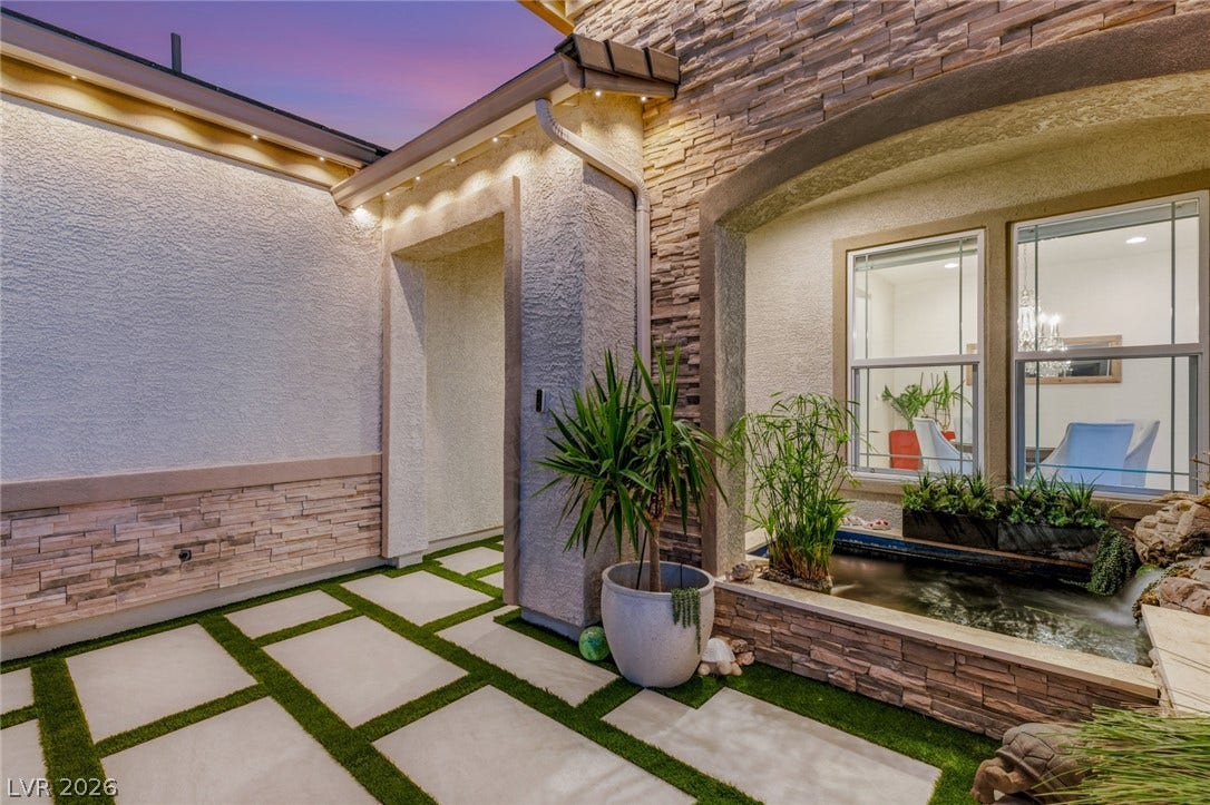 A stone-accented courtyard path leads past a built-in water feature toward the private entry.