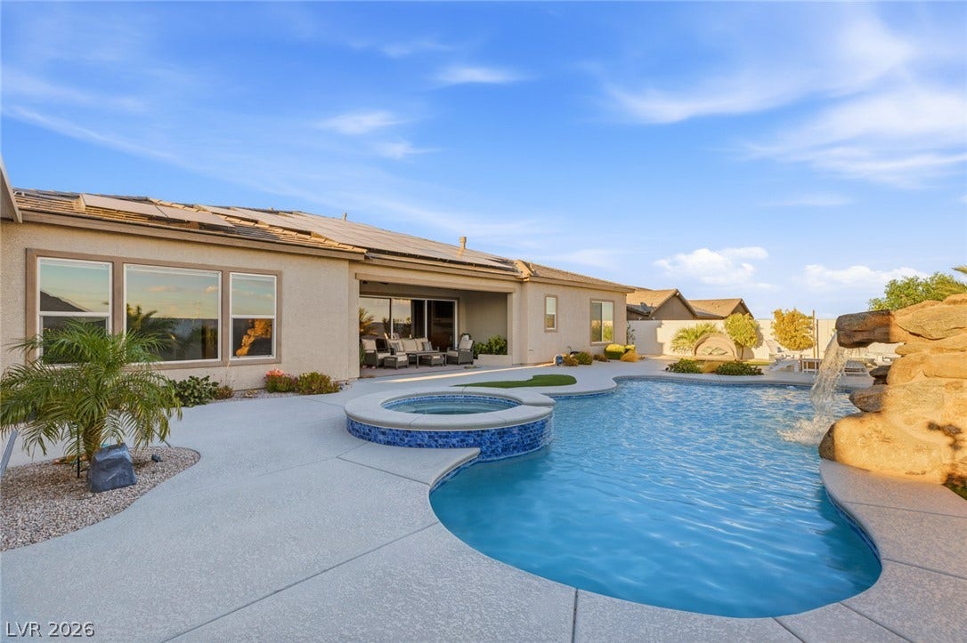 A sparkling swimming pool and raised spa highlight the expansive concrete patio.