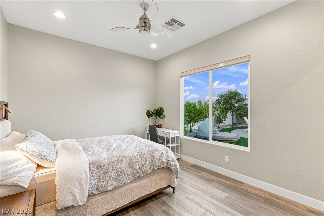 A large picture window frames verdant backyard views from this modern bedroom.