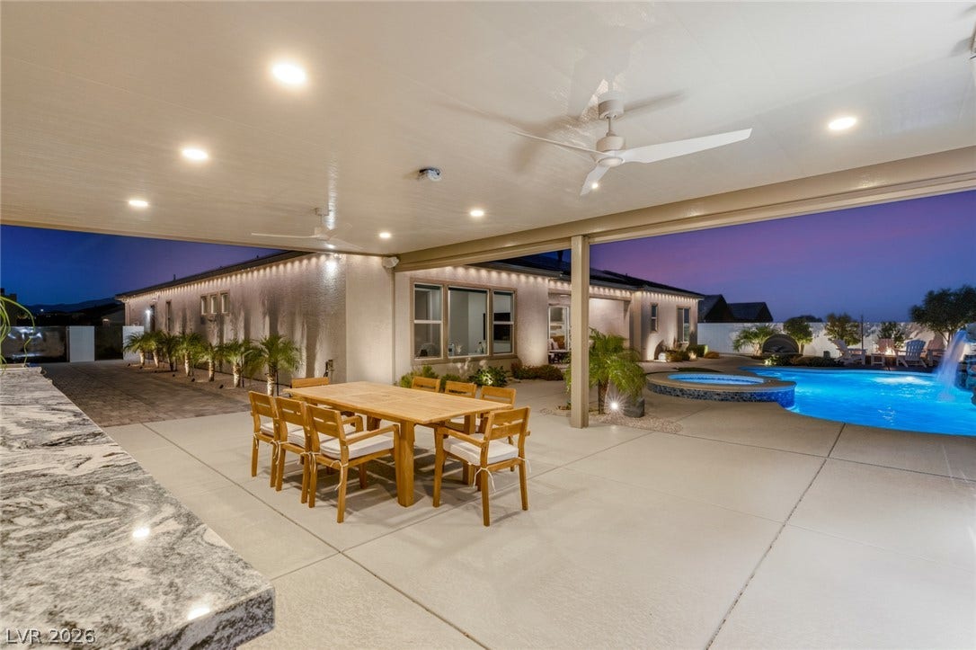 A spacious covered patio overlooks a sparkling swimming pool under evening skies.