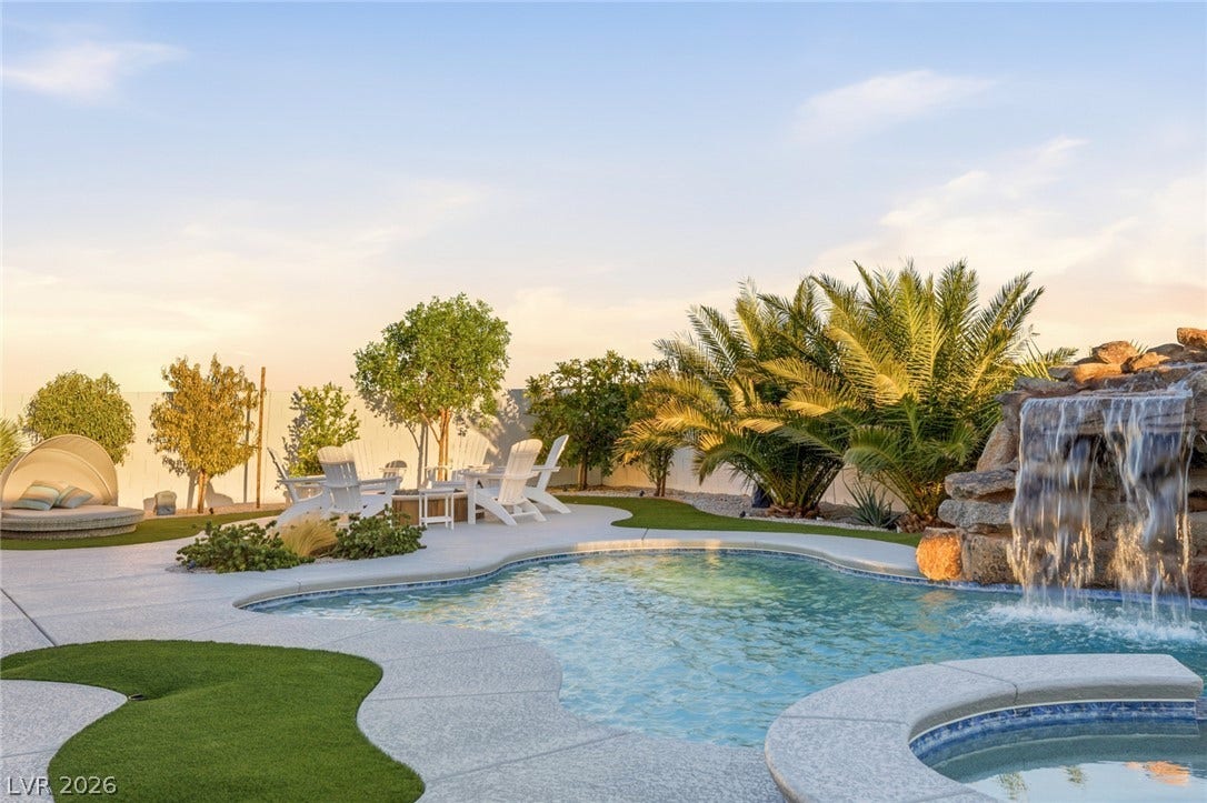 An inviting backyard oasis features a curved pool complete with a cascading stone waterfall.