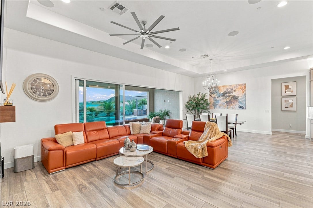 A spacious open-concept living area features wood-look tile floors and towering ceilings.
