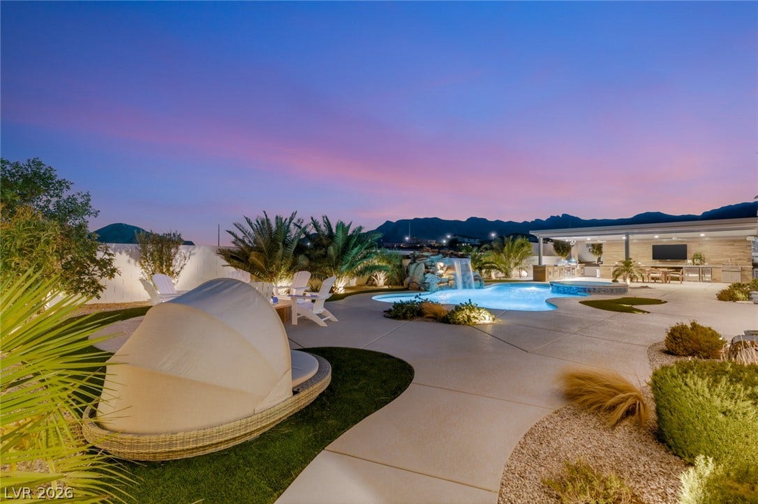 A sparkling pool with a waterfall highlights this spacious backyard against a mountain backdrop.