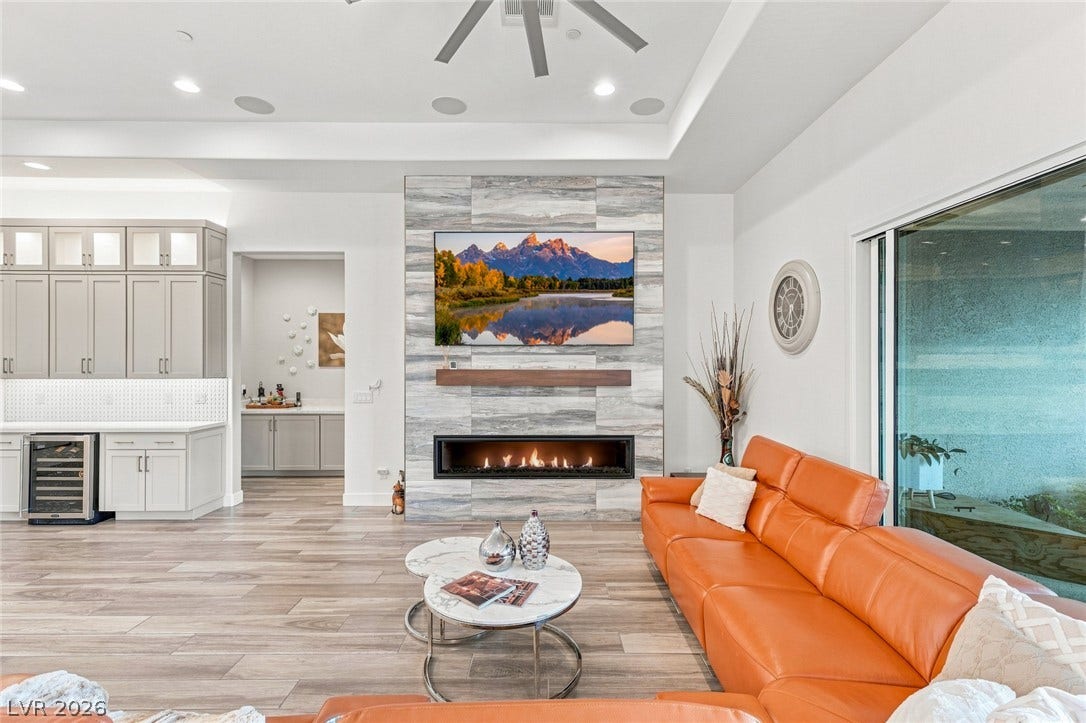 Smooth wood-look flooring and a modern stone fireplace wall define this airy living space.