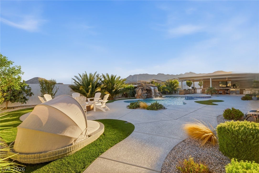 An inviting backyard oasis features a custom swimming pool framed by distant mountain views.