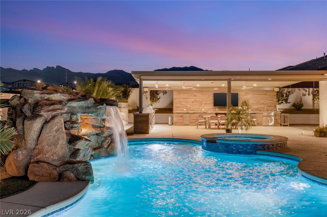 A magnificent rock waterfall anchors this resort-style backyard retreat framed by mountain views.