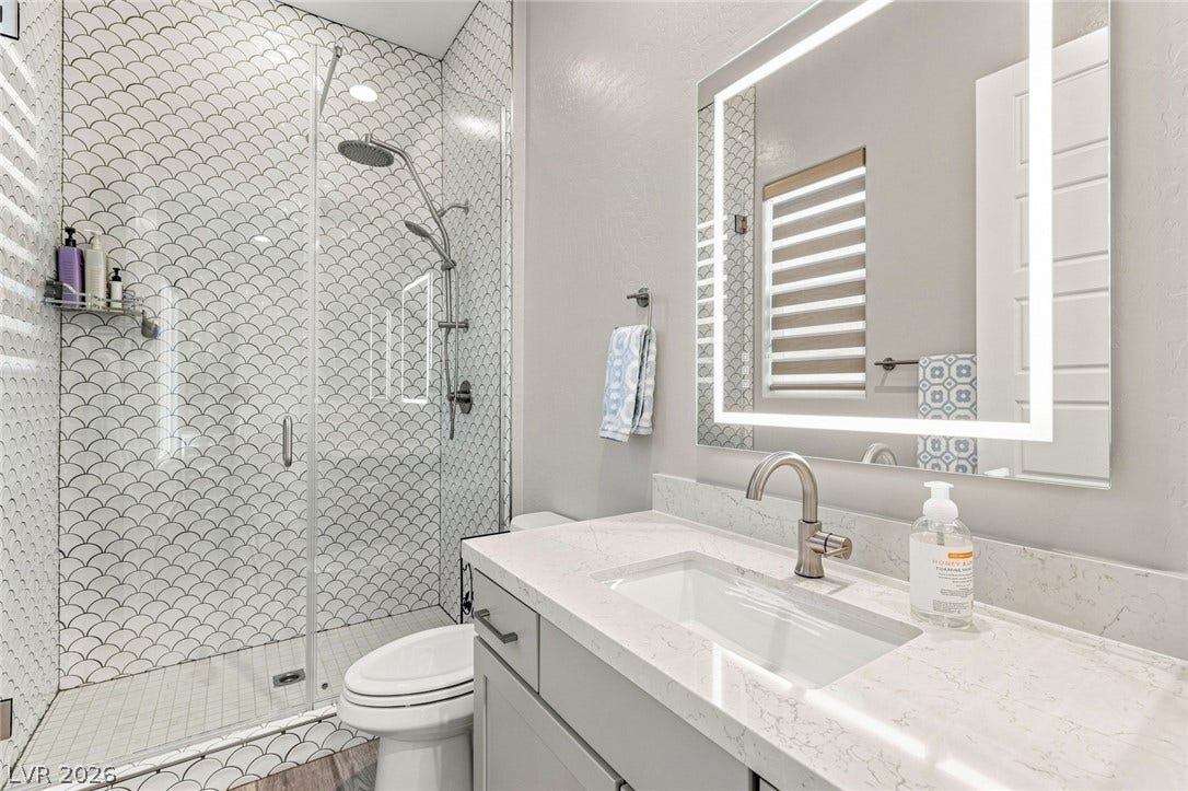 Modern stone countertops and patterned tile walling elevate this bathroom space.