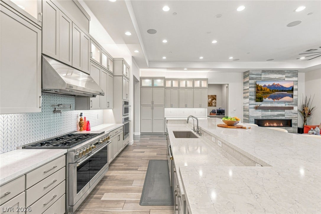 An open kitchen showcases extensive stone countertops alongside professional-grade appliances.