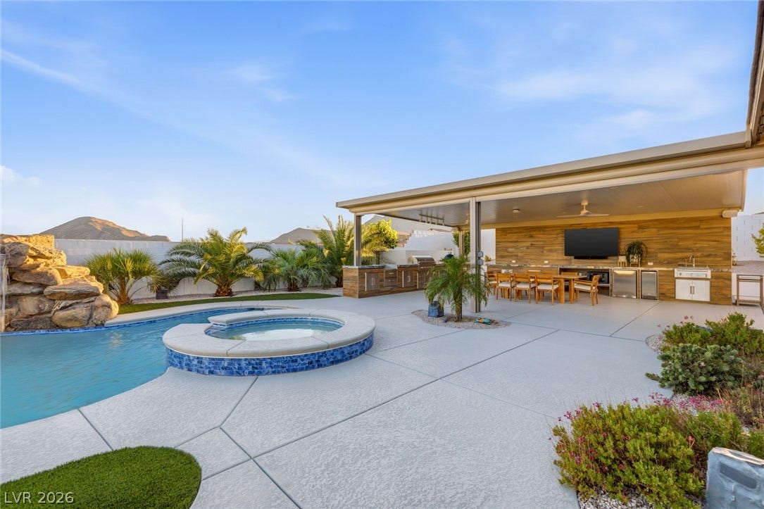 An expansive outdoor patio area adjoins a custom pool with integrated spa and mountain views.