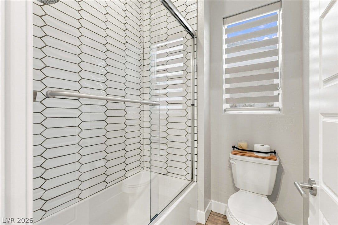 Geometric wall tile highlights a contemporary shower and tub combination next to a bright window.