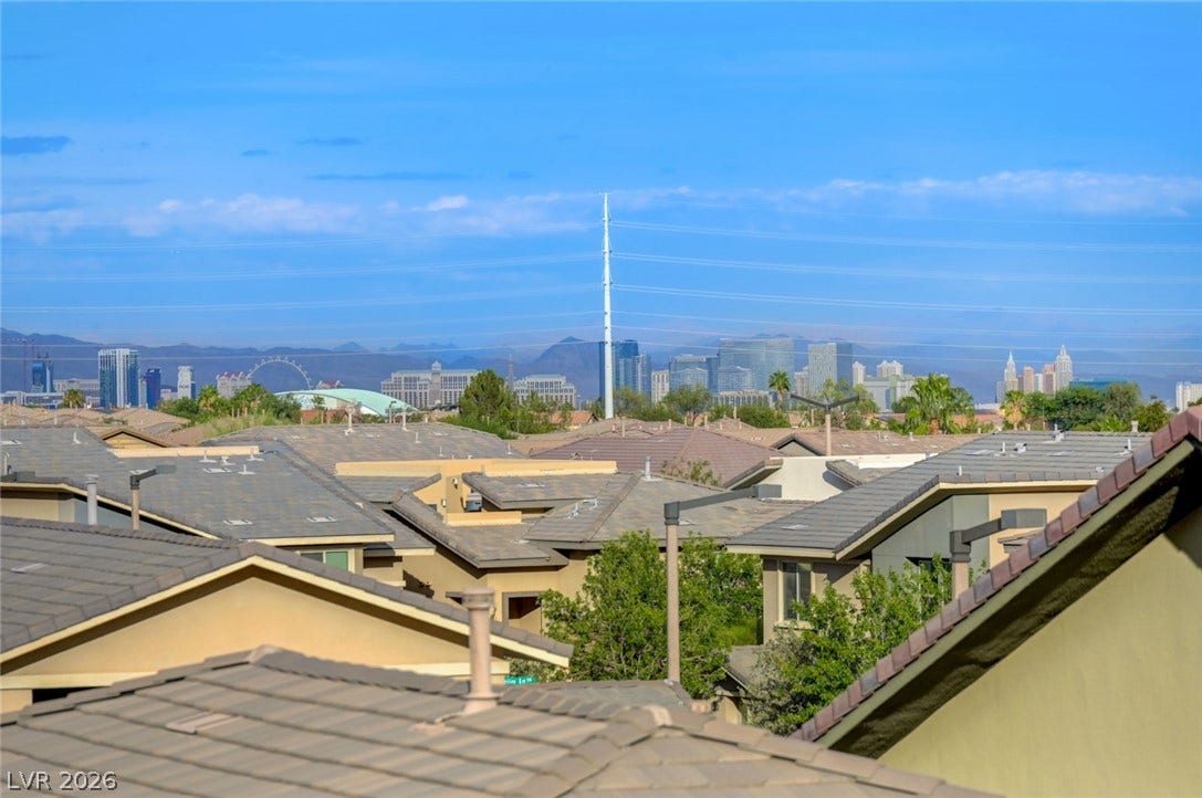 5608 Beckett Hill Court, Las Vegas, NV 89135 Distant city skyline views rise above the surrounding residential rooftops under a clear blue sky.