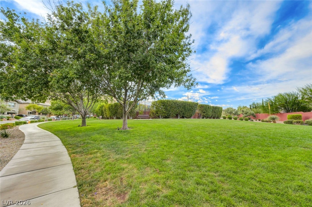 5608 Beckett Hill Court, Las Vegas, NV 89135 Manicured green space with mature shade trees bordered by a winding concrete walkway.