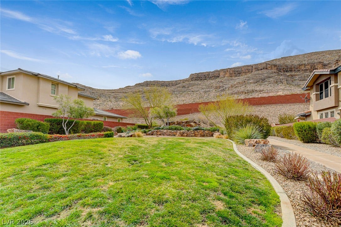 5608 Beckett Hill Court, Las Vegas, NV 89135 Dramatic mountain vistas rise above a manicured green lawn and professional desert landscaping.
