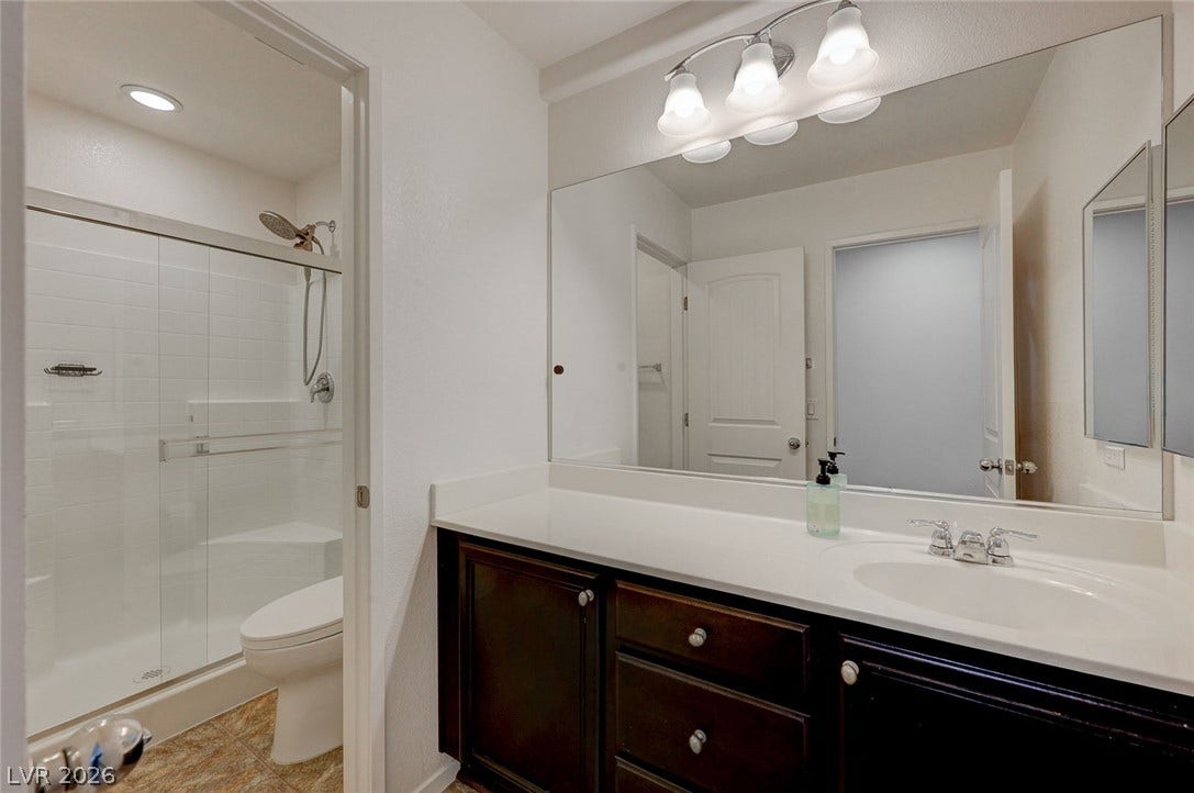 5608 Beckett Hill Court, Las Vegas, NV 89135 Dark cabinetry contrasts beautifully with the light solid-surface vanity countertop in this bathroom.