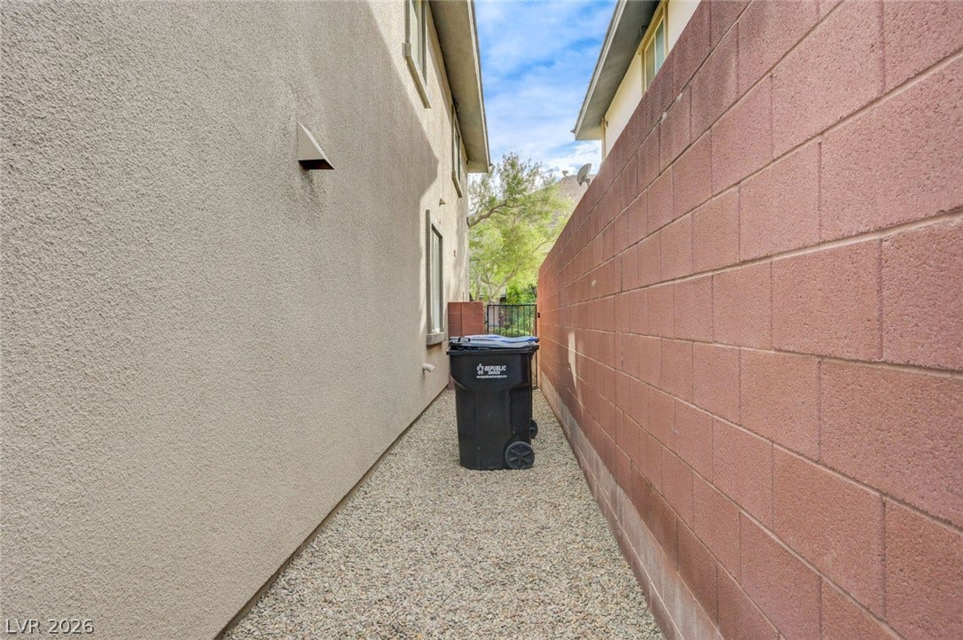 5608 Beckett Hill Court, Las Vegas, NV 89135 A gravel side path is bordered by stucco walls and a tall brick fence.