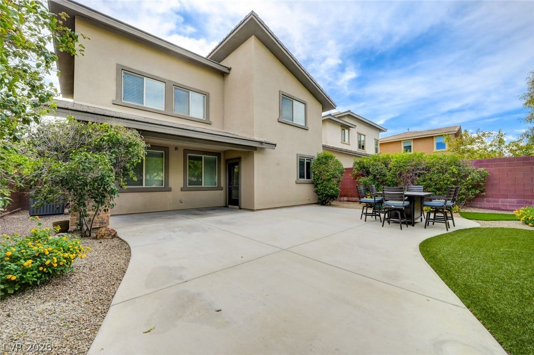 5608 Beckett Hill Court, Las Vegas, NV 89135 An expansive concrete patio connects the stucco exterior to a manicured lawn.