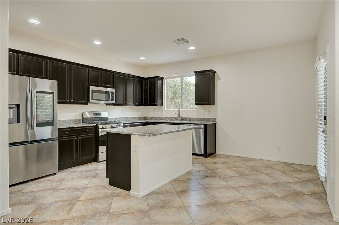 5608 Beckett Hill Court, Las Vegas, NV 89135 Dark cabinetry and granite countertops anchor this kitchen alongside tiled flooring.