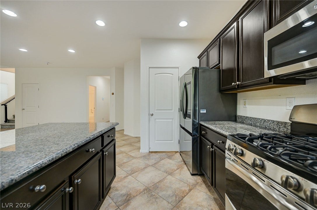 5608 Beckett Hill Court, Las Vegas, NV 89135 Rich dark cabinetry and stone countertops anchor this functional cooking space.