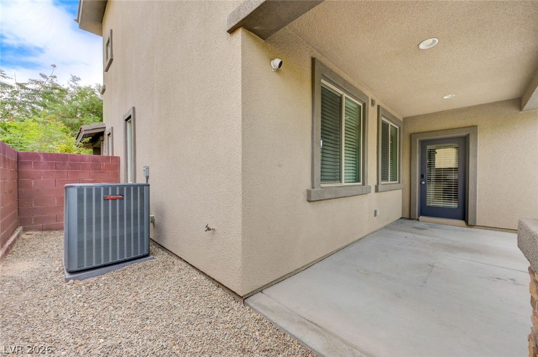 5608 Beckett Hill Court, Las Vegas, NV 89135 A covered concrete patio provides a shaded outdoor space adjacent to the stucco exterior.