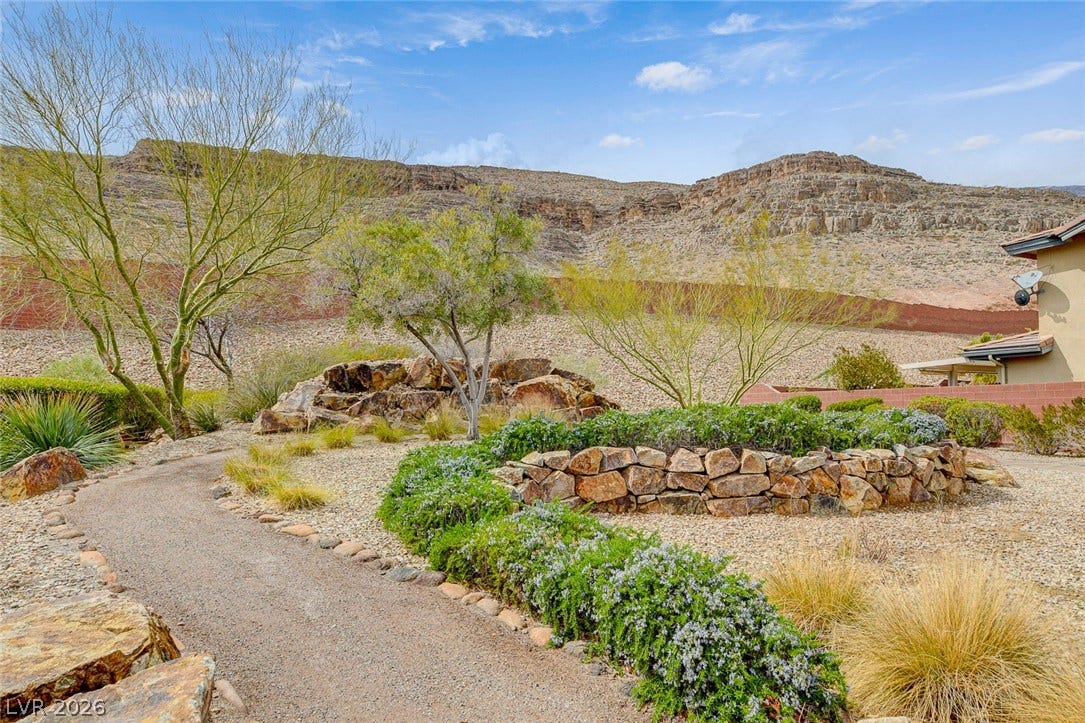 5608 Beckett Hill Court, Las Vegas, NV 89135 Rugged stone retaining walls border a gravel path set against a dramatic desert mountain backdrop.