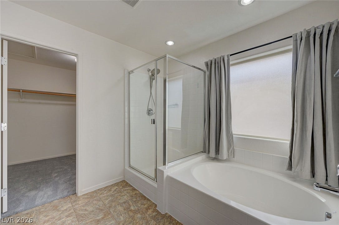 5608 Beckett Hill Court, Las Vegas, NV 89135 A glass-enclosed walk-in shower sits adjacent to a deep soaking tub under a large window.