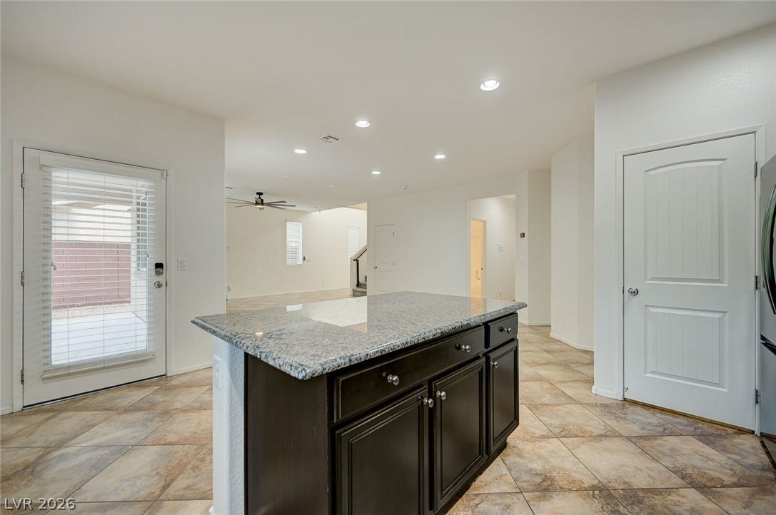 5608 Beckett Hill Court, Las Vegas, NV 89135 Polished granite countertops and classic tile flooring define this airy, open-concept kitchen.