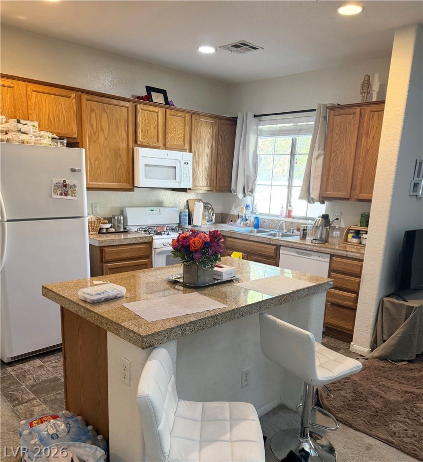 6408 Yucca Ridge Court, North Las Vegas, NV 89084 Warm wood cabinetry and granite-patterned surfaces anchor this functional, light-filled kitchen space.
