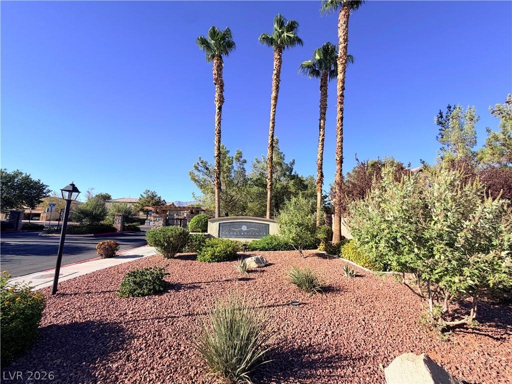 6408 Yucca Ridge Court, North Las Vegas, NV 89084 Towering palm trees frame the gated entrance under clear blue desert skies.