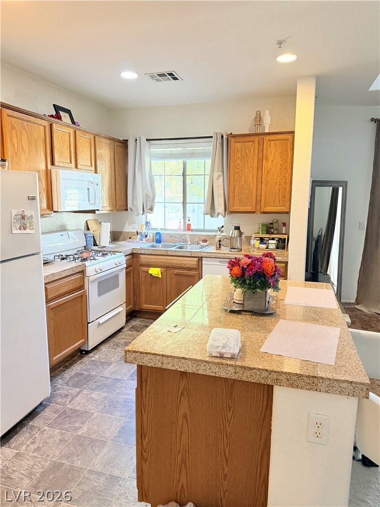 6408 Yucca Ridge Court, North Las Vegas, NV 89084 Rich wood cabinetry and a central tile island define this efficient workspace.