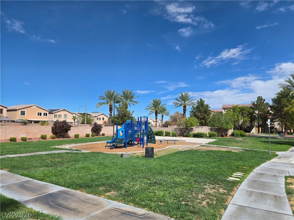5935 Nuevo Leon Street, #2, North Las Vegas, NV 89031 Green grass surrounds the community playground area under clear desert skies.