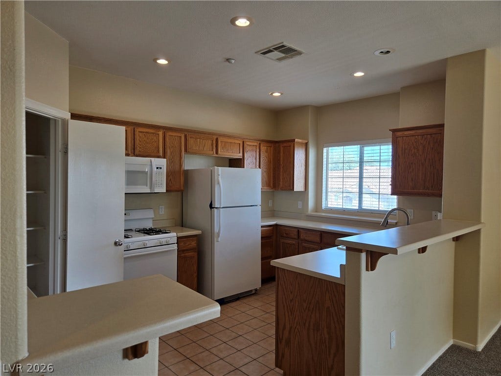 5935 Nuevo Leon Street, #2, North Las Vegas, NV 89031 Ample wooden cabinetry and recessed lighting highlight this functional kitchen space with tile flooring.