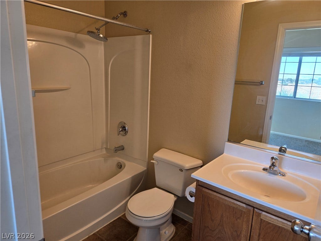 5935 Nuevo Leon Street, #2, North Las Vegas, NV 89031 Functional bathroom layout features a shower and tub combination next to a classic wooden vanity.