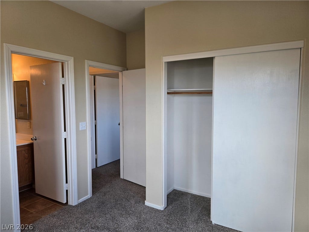 5935 Nuevo Leon Street, #2, North Las Vegas, NV 89031 Comfortable bedroom carpet leads toward a built-in closet and adjacent rooms.