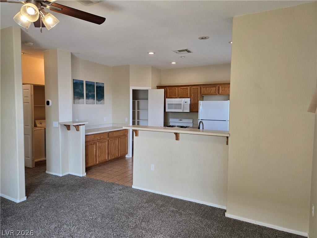 5935 Nuevo Leon Street, #2, North Las Vegas, NV 89031 An open floor plan connects the carpeted living space directly to the kitchen.