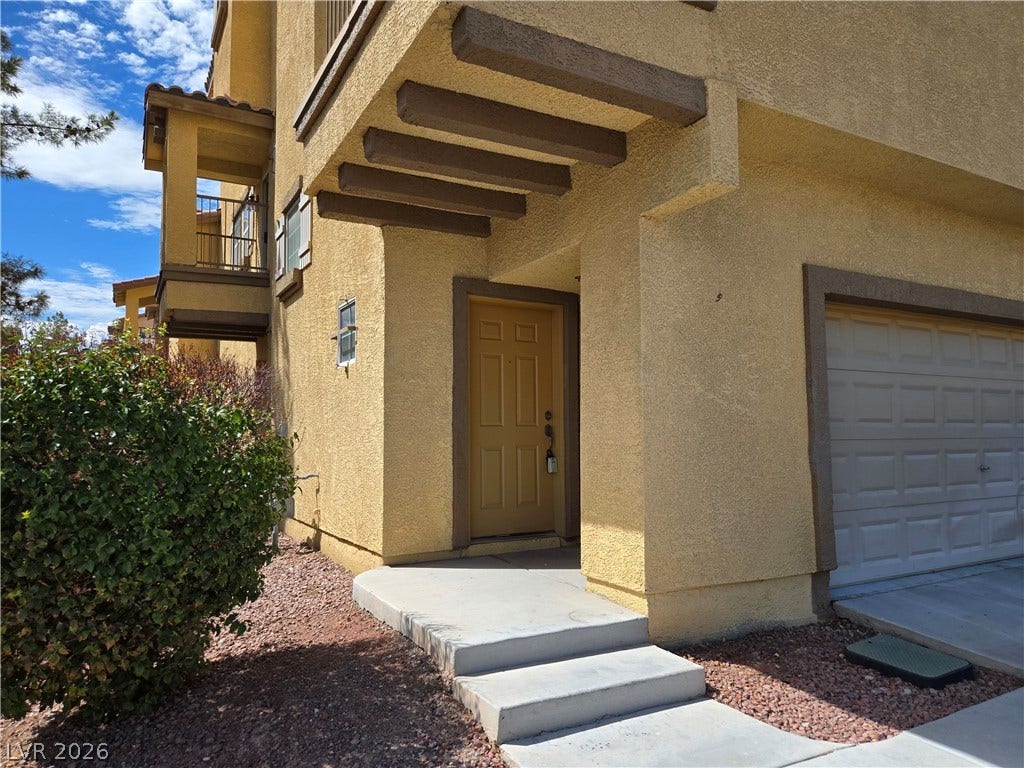 5935 Nuevo Leon Street, #2, North Las Vegas, NV 89031 Concrete steps lead to a recessed entryway featuring stucco siding and integrated wooden accents.
