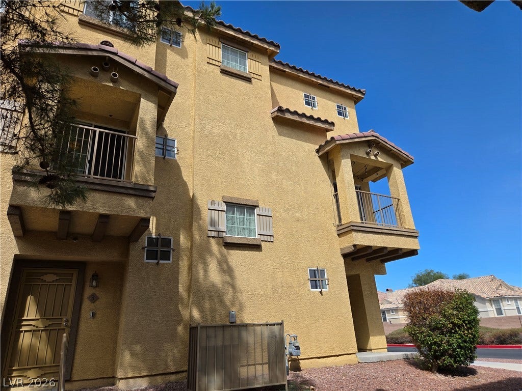 5935 Nuevo Leon Street, #2, North Las Vegas, NV 89031 Multi-level Mediterranean-style architecture features integrated balconies and warm stucco finishes under a clear blue sky.