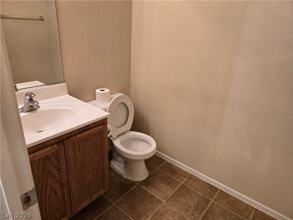 5935 Nuevo Leon Street, #2, North Las Vegas, NV 89031 A classic wood vanity and tiled floor define this neat half bathroom space.