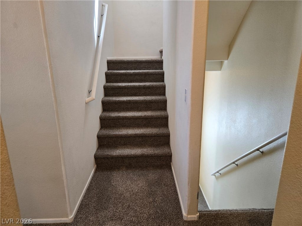 5935 Nuevo Leon Street, #2, North Las Vegas, NV 89031 Carpeted stairs with white handrails connect the different levels of the home.