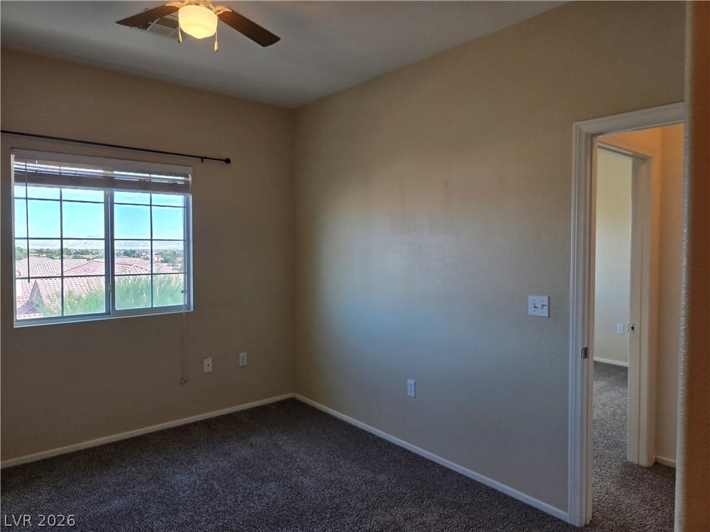 5935 Nuevo Leon Street, #2, North Las Vegas, NV 89031 A secondary bedroom features neutral-toned carpet flooring and a multi-lite window framing neighborhood views.