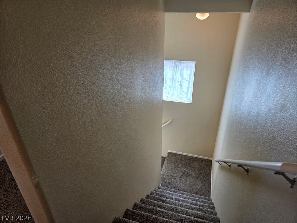 5935 Nuevo Leon Street, #2, North Las Vegas, NV 89031 A carpeted staircase features neutral walls and a handrail leading to a mid-level landing.