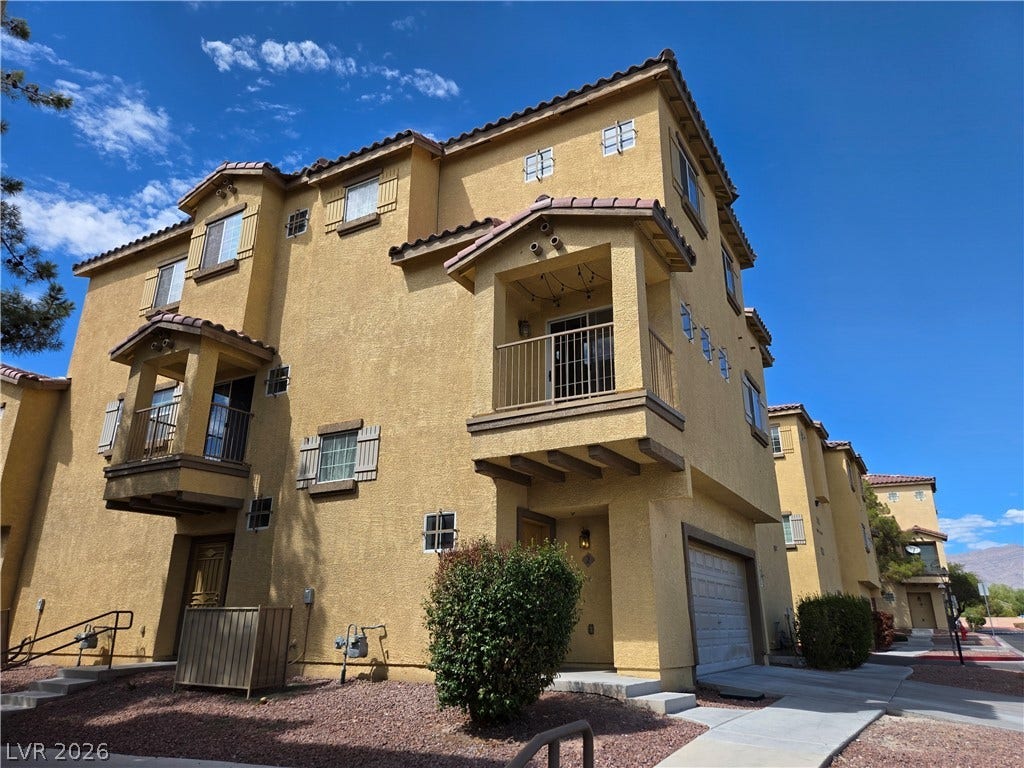 5935 Nuevo Leon Street, #2, North Las Vegas, NV 89031 Multi-level Mediterranean-inspired architecture featuring private balconies and an attached garage under clear blue skies.