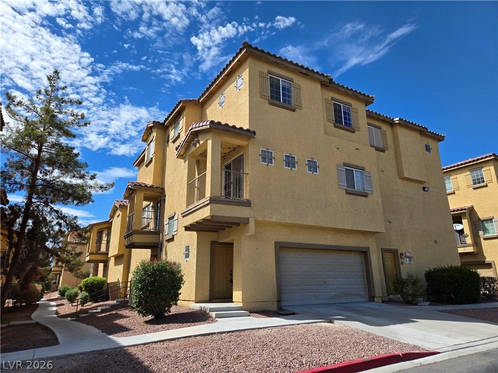 5935 Nuevo Leon Street, #2, North Las Vegas, NV 89031 Multi-level Mediterranean-style townhome featuring stucco walls, a private balcony, and an attached garage.