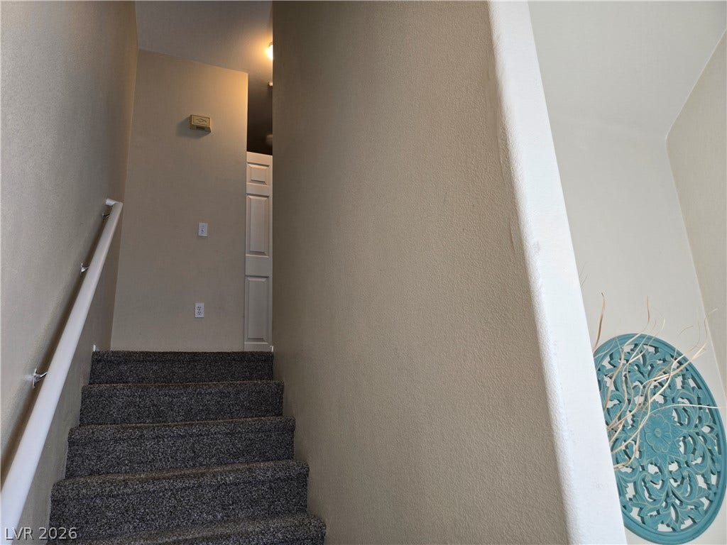 5935 Nuevo Leon Street, #2, North Las Vegas, NV 89031 Carpeted stairs lead upward alongside neutral walls and a simple white handrail.
