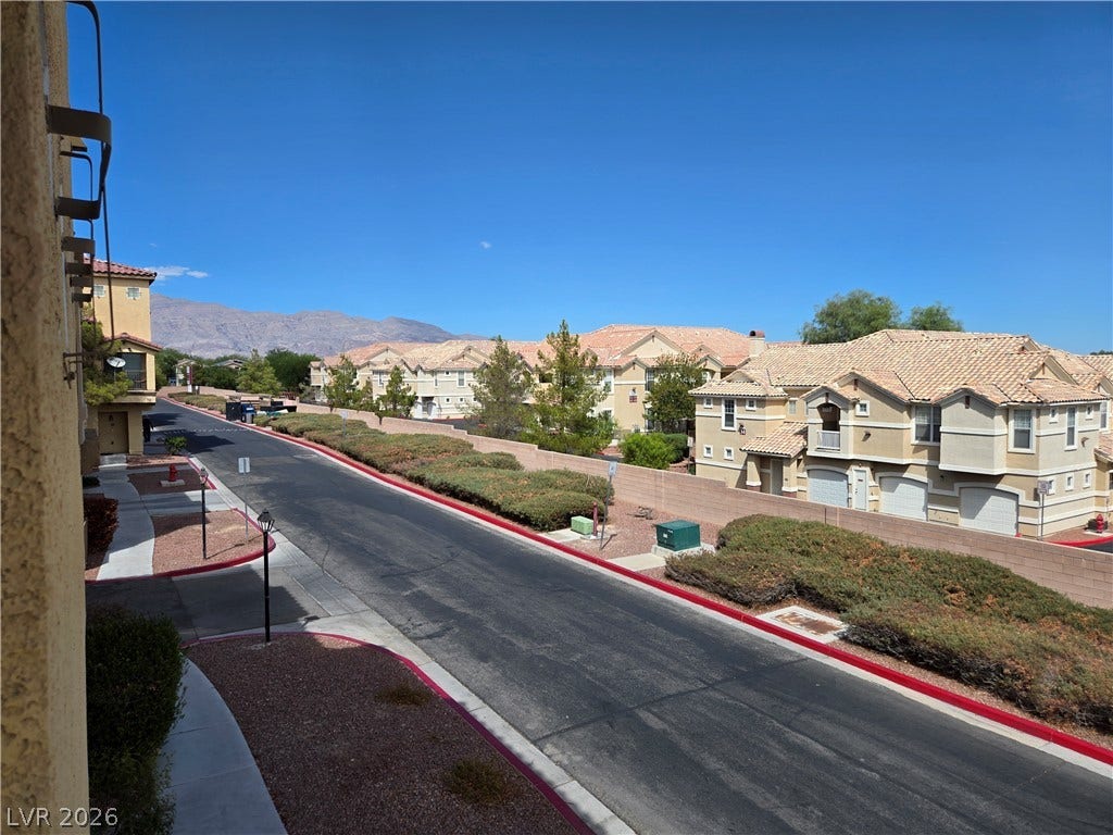 5935 Nuevo Leon Street, #2, North Las Vegas, NV 89031 Distant mountains frame the neighborhood streetscape lined with tile-roofed residences.